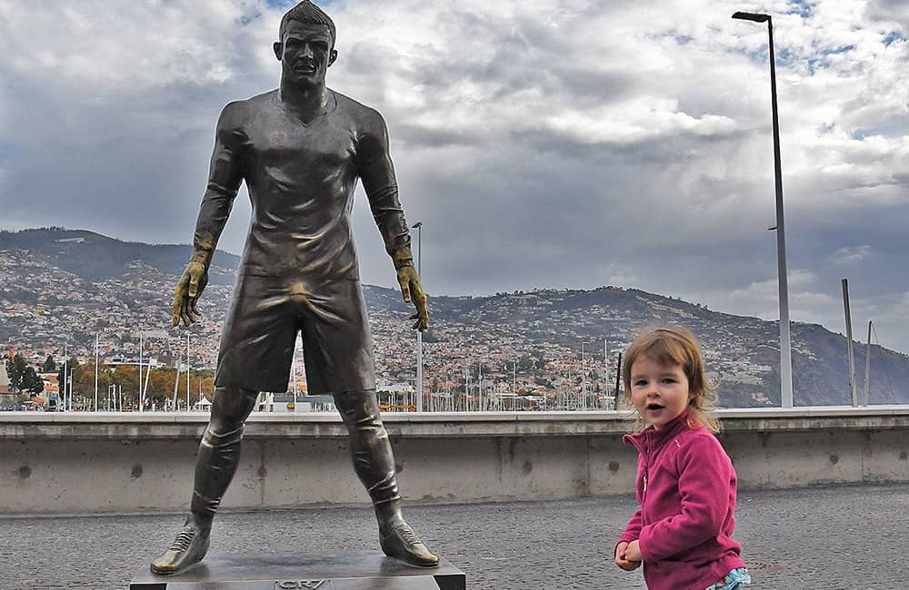 a little girl next to Ronald football star cooper statue in Funchal harbour.
