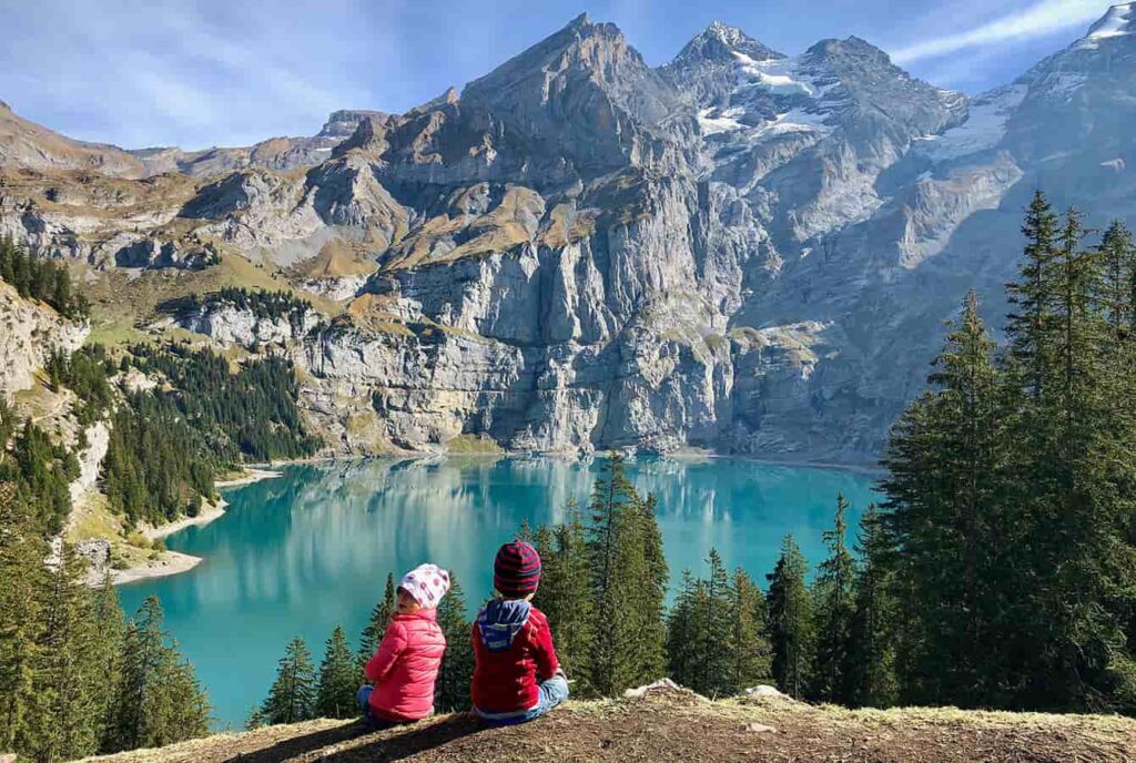 young children with red jackets sitting at the Läger viewpoint at the Oeschinensee