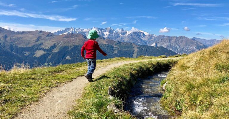 Ein Junge in einer roten Jacke wandert in einem familienfreundlichen Zug im Wallis.