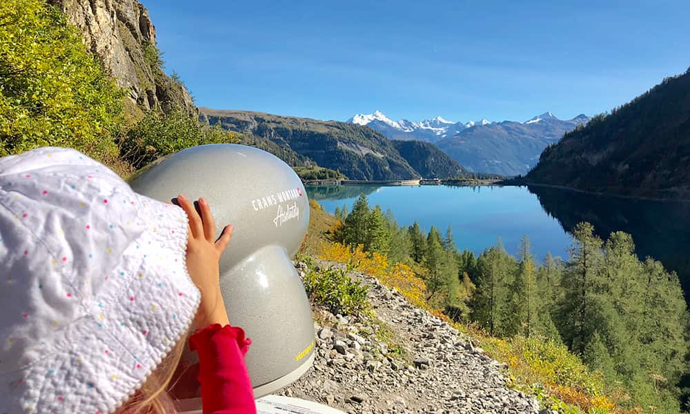 a little girl looking through a mountain finder at lake Tseuzier on the family friendly hike in valais