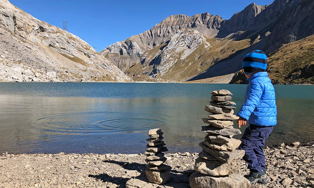 a boy in a blue jacket by the mountain lake of the Sanetsch pass during a trail