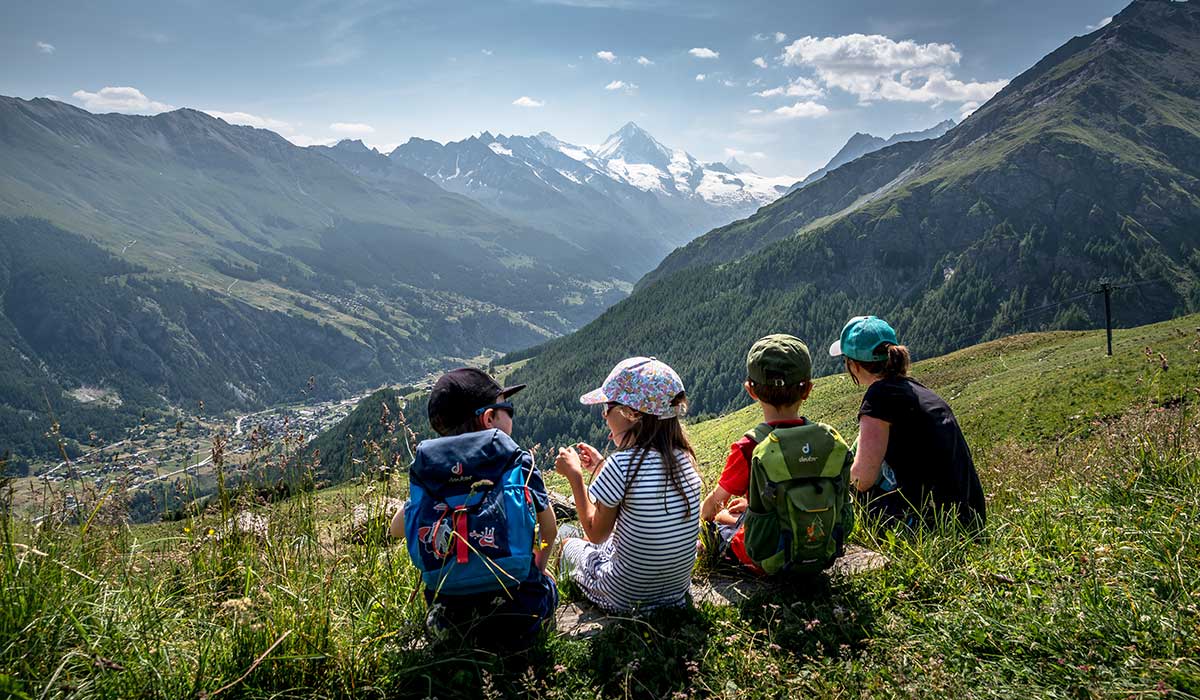 children sitting in the gras and looking at la dent blanch in Evolène Valais