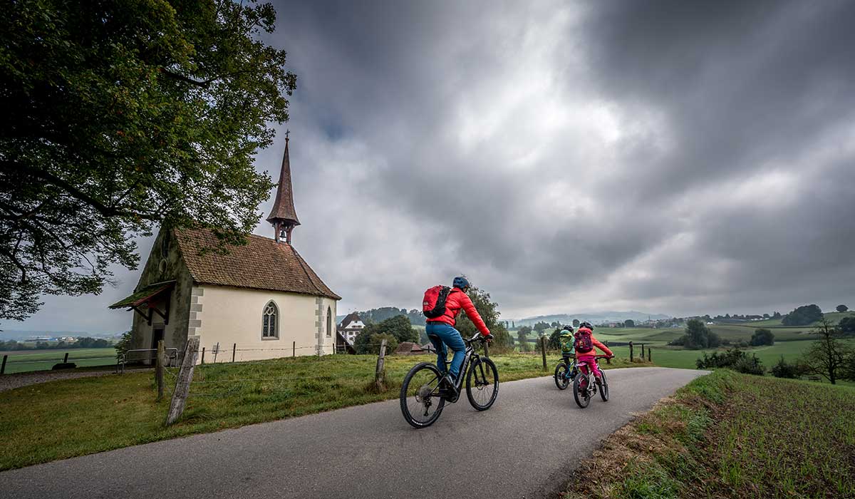 Familie auf dem Fahrrad in der Region Willisau bei einer Kapelle