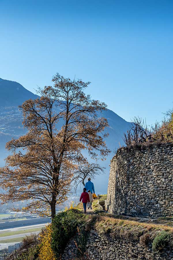 family hiking along a bisse, Mont d'Orge in Valais. Best places to visit in Autumn
