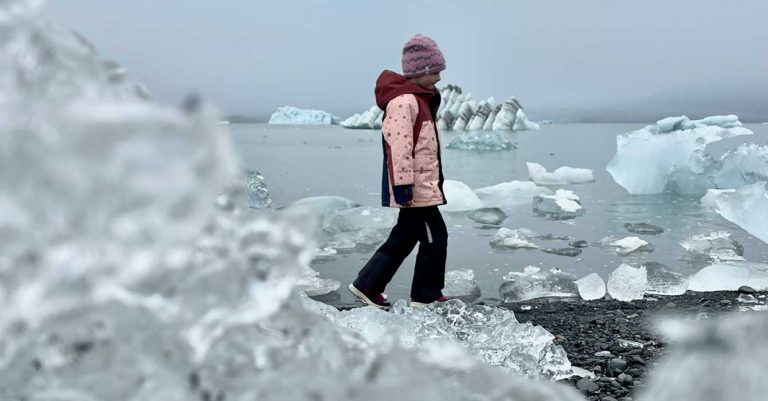 girl in the ice lagoon by a glacier in Iceland- winter clothing