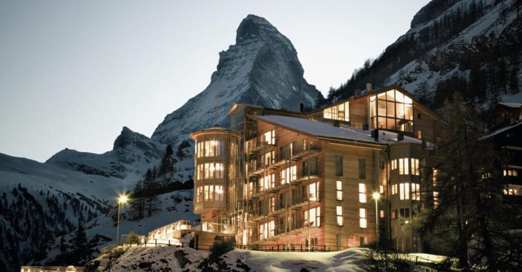 hotel in zermatt during the night with all lights on and the Matterhon in the back