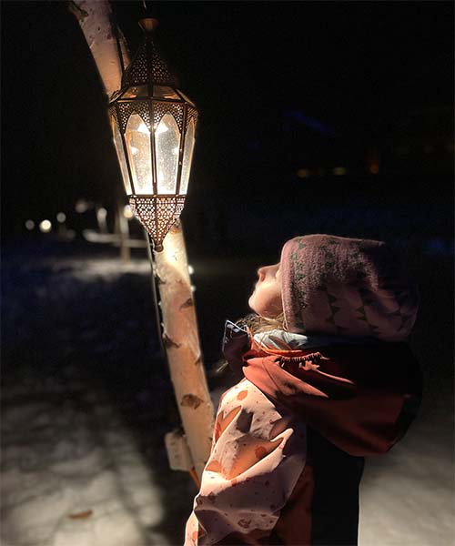 girl looking into a lanterne covered with snow