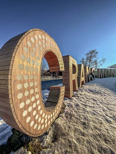 a wooden sign saying Crans Montana in the snow