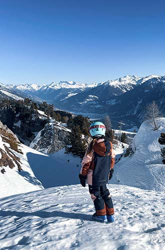 a girl standing at the top of a rocky snowy mountain in Switzerland