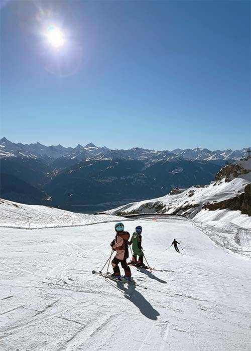 a family sking down a piste in crans montana