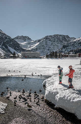 children by a semi frozen lake in Arosa