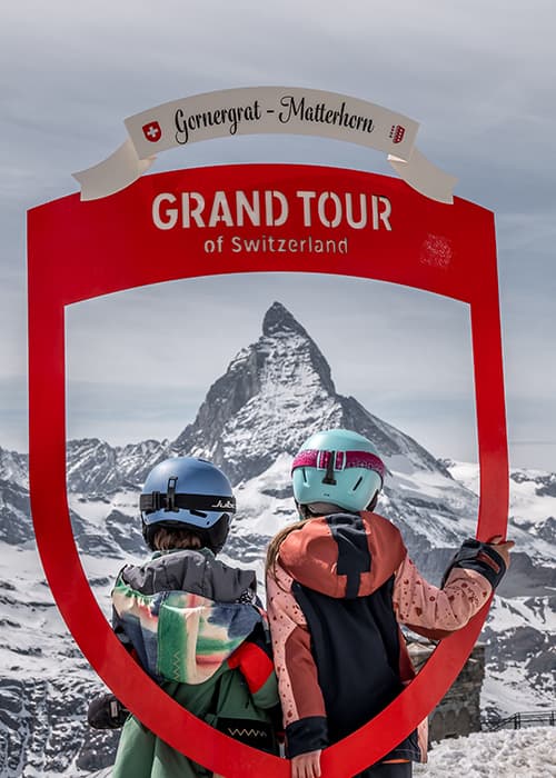 Children standing on a photo point in Switzerland whilst skiing in Zermatt