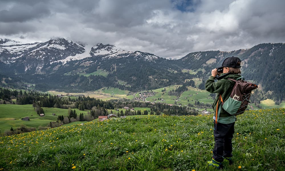 a boy looking through his binoculars over Lauenen Valley by Gstaad