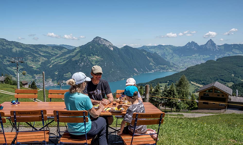 a family eating lunch at the mountain restaurant stockhütte with lake Lucerne in the background