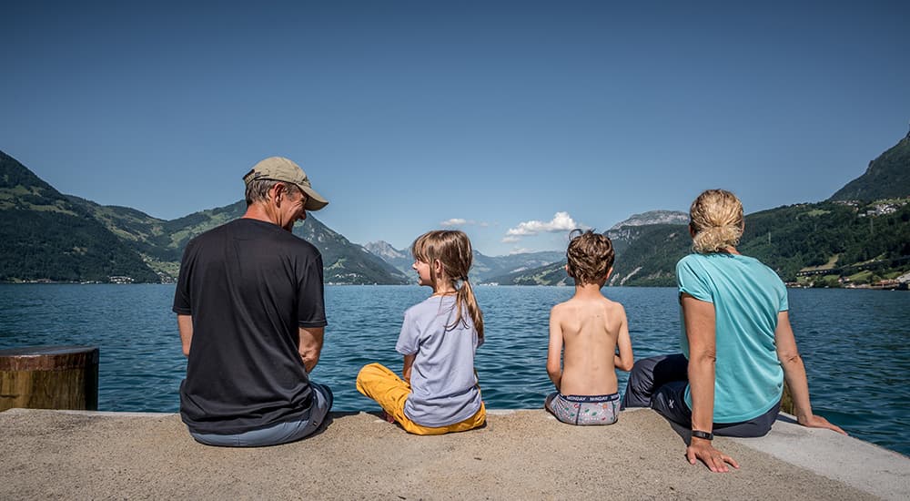 a family sitting at the shore of lake lucerne at beckenried