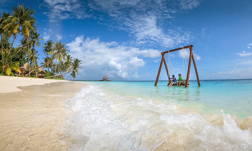 children sitting on a water swing on an maldive resort isalnd 