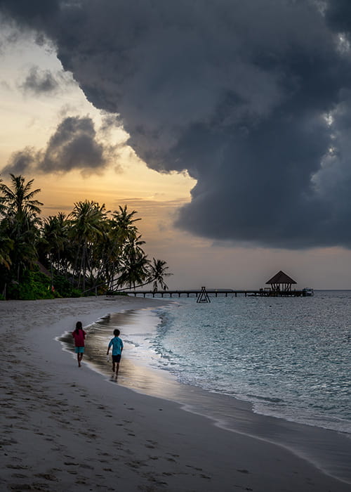 children walking during sunset on a beach in the maldives