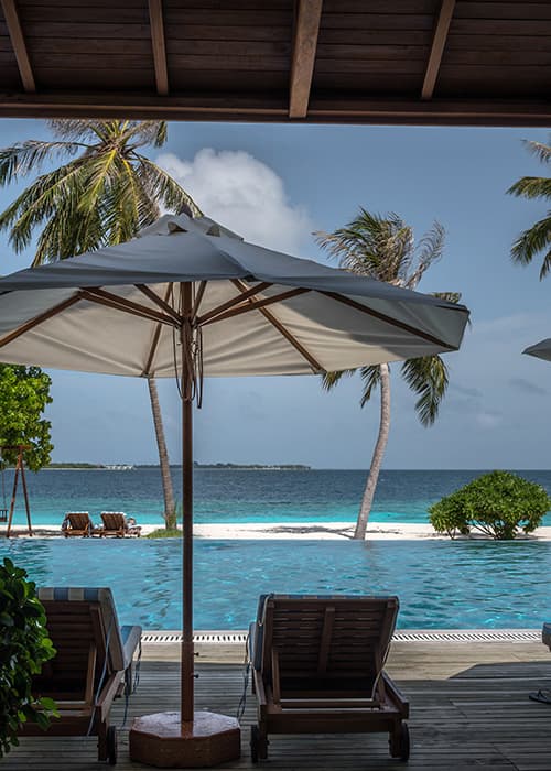 view from a sunbed over the pool in to the ocean from an island in the Maldives