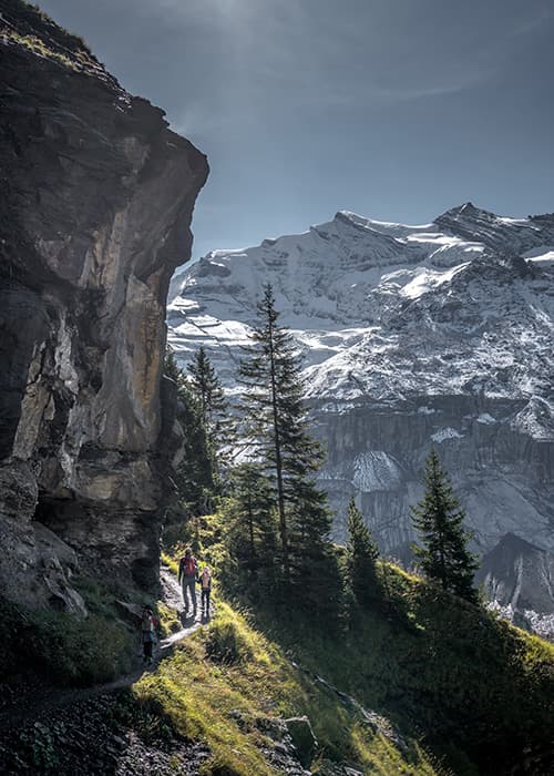 family hiking in oeschinen along a narrow path