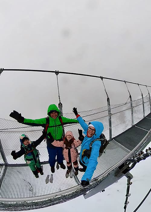a family standing on the Titlis cliff walk duirng a stormy winters day