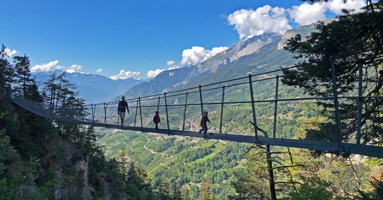family crossing a suspension bridge whilst hiking Bisse du Torrent Neuf in valais