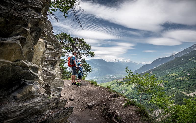 family standing on a mountain drop off along a hike in Valais
