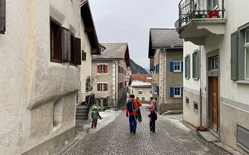 family carrying sledges and walking down the main street of a Swiss village