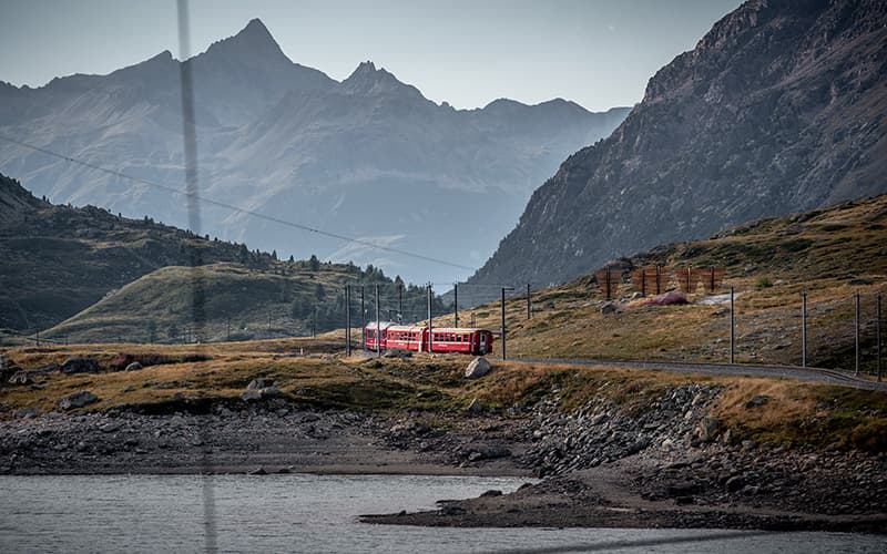 a train next to a lake when travelling Switzerland by train