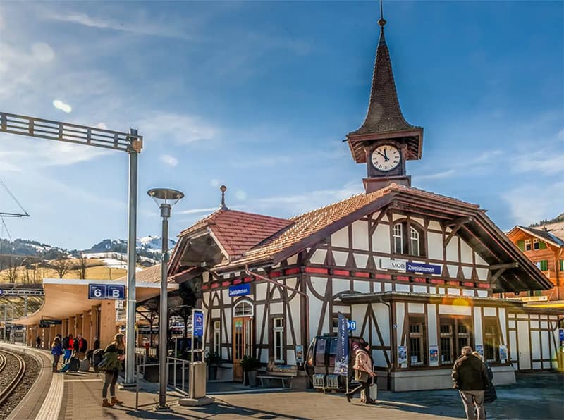 a beautiful train station building with a clock tower in Zweisimmen Switzerland