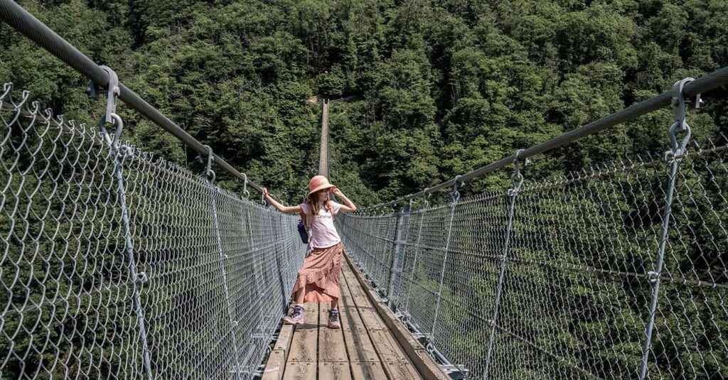 a girl standing in the middle of the suspencion bridge at the Carasc Tibetan bridge in ticino