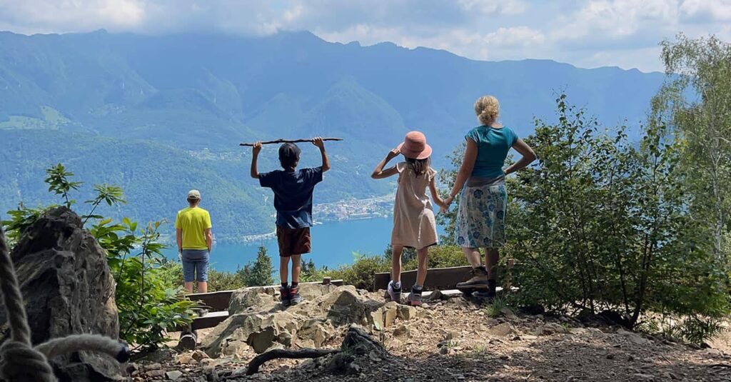 a family in hiking gear looking down on to lake lugano whilst on the Morcote hiking trail