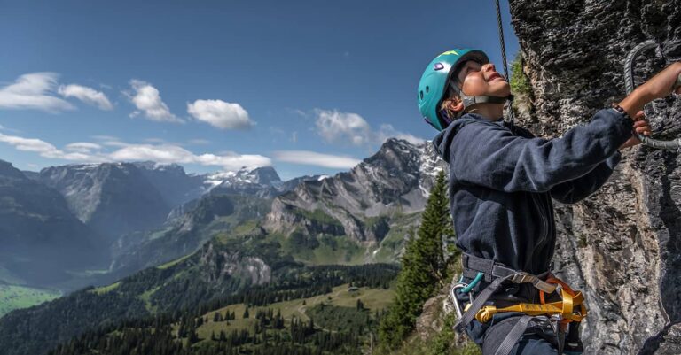 a boy on the Braunwald Via Ferrata with mountains in the back