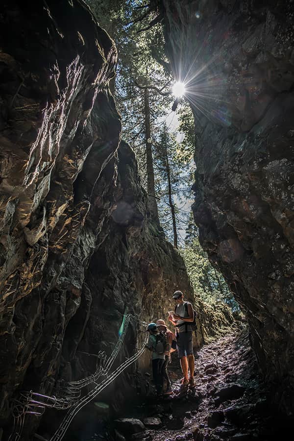 father with children hiking in Braunwald along a canyon in the forest