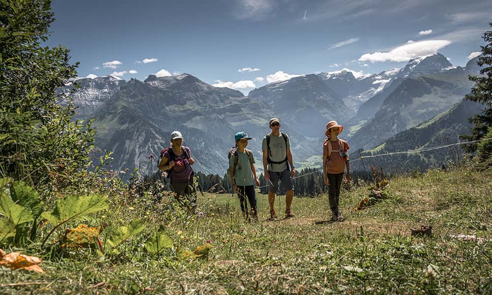 a family hiking in Braunwald up a meadow