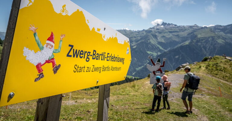 a family hiking in Braunwald at the Zwerg Bartli theme trail