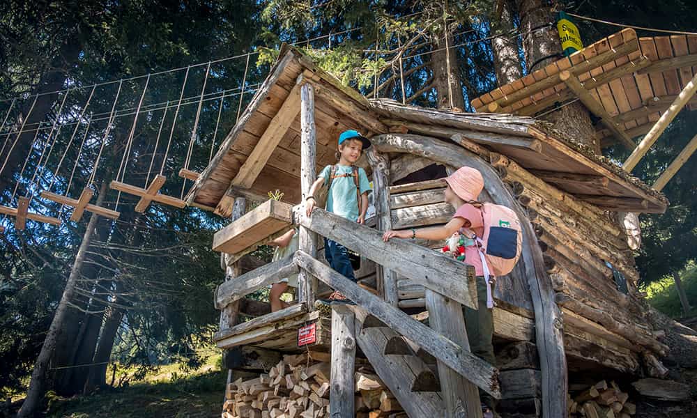 children playing at a wooden gnome house in the forest