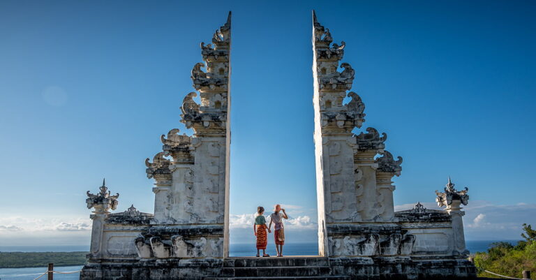 children standing at a bali gate looking over the sea