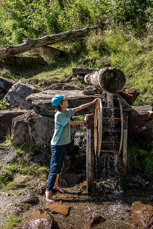 a boy playing at a water mill barefoot