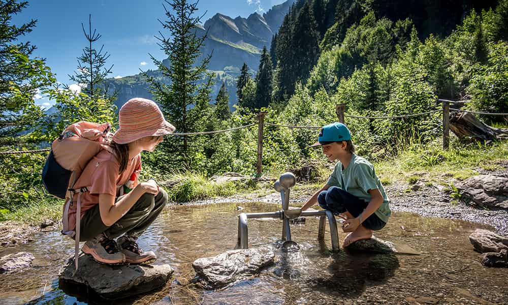 children playing at a water station along a hiking trail in Braunwald