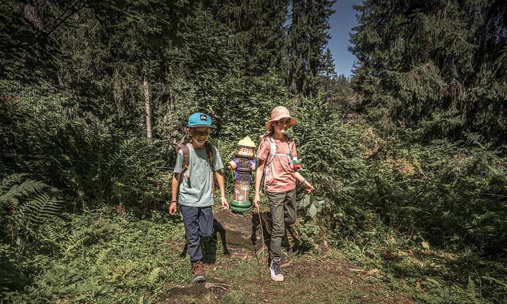 a boy and a girl walking in the forest in the Swiss village Braunwald