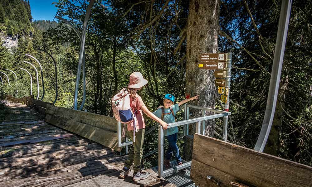 children staying at a Zwerg Bartli Erlebsnisweg hiking junction indication different pathes