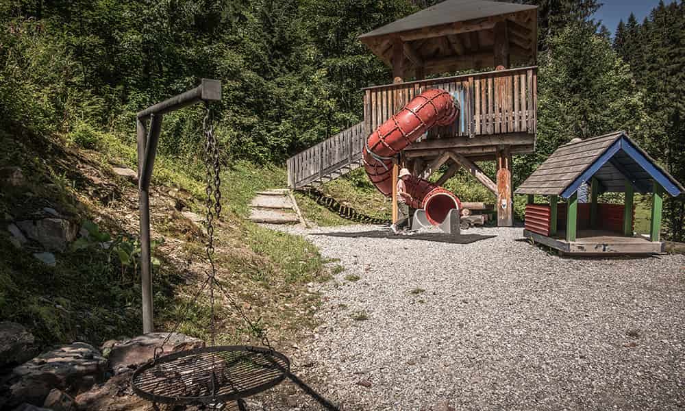 a play ground with a large slide and a BBQ station along a hiking trail in Braunwald