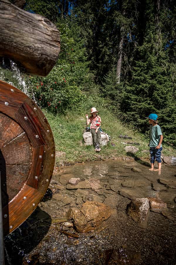 children playing at a water source along the Zwerg Bartli theme trail whilst hiking in the Swiss village Braunwald