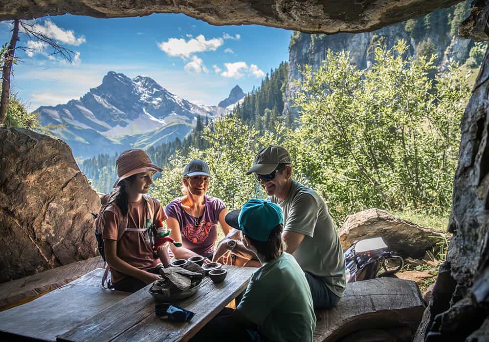 a family sitting in a cave at the Zwerg Bartli them trail whilst hiking in Braunwald