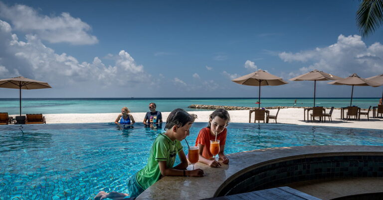 children at the bar drinking cocktails whilst parents are in the pool