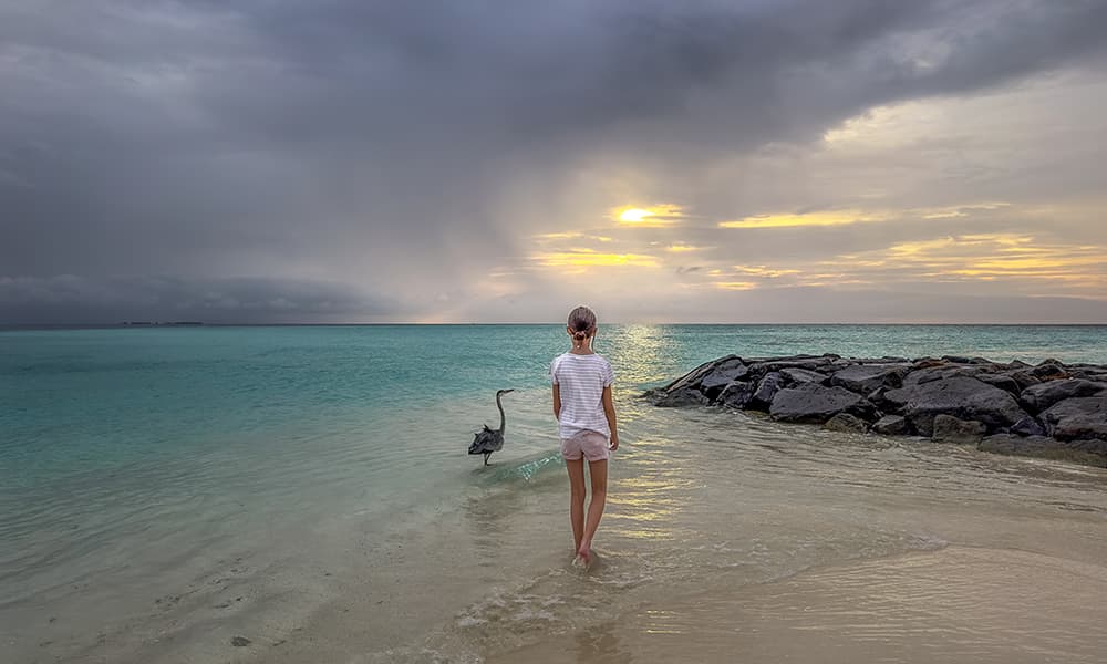 a girl with a fishrayer at the beach in Fulidhoo with a stormy sky