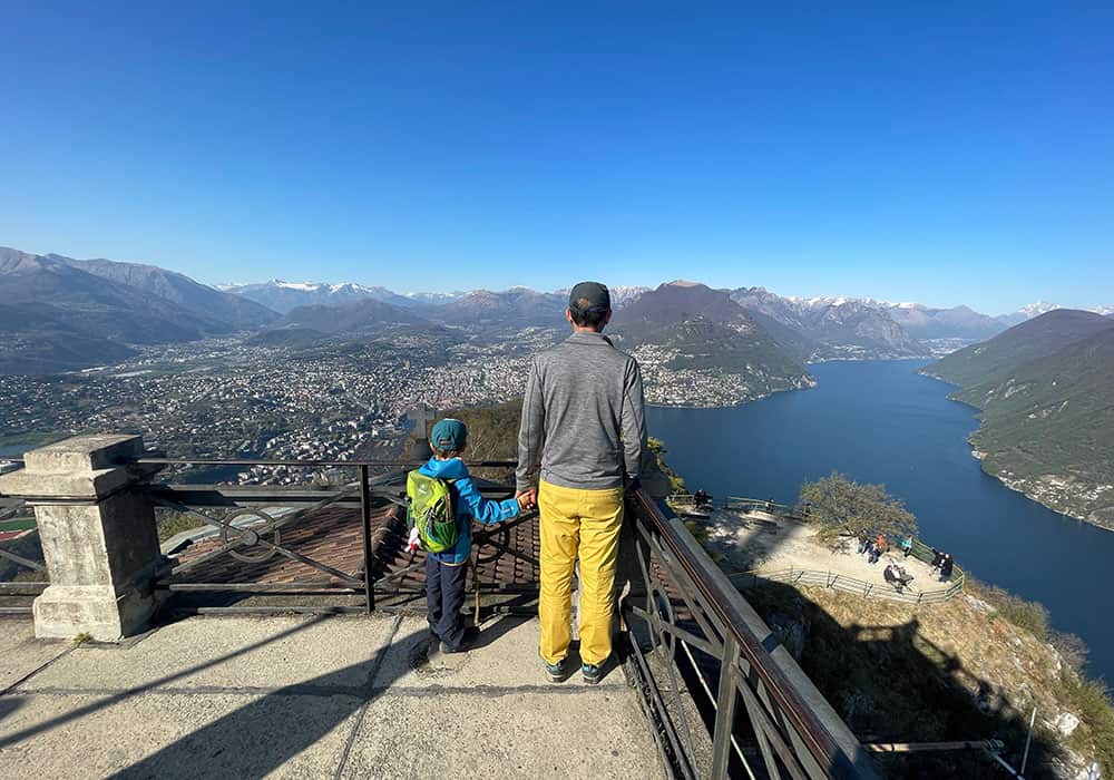 A father and son standing at the Swiss viewpoint San Salvatore in Ticino on a sunny day