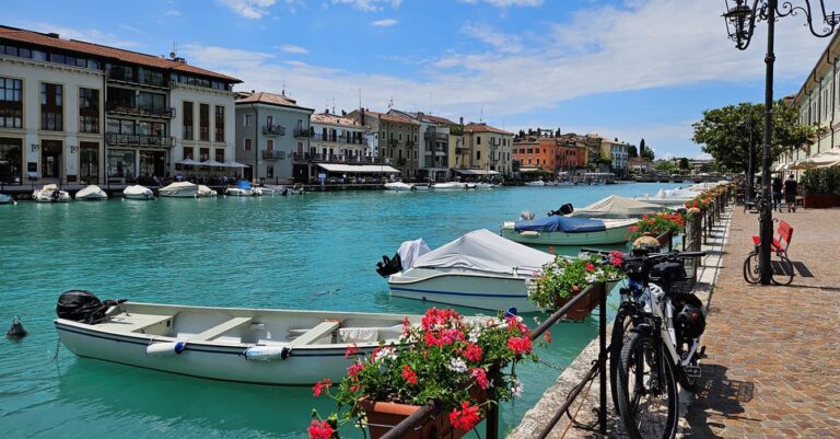 beautiful fishing boats with red flowers and houses at lake garda italy