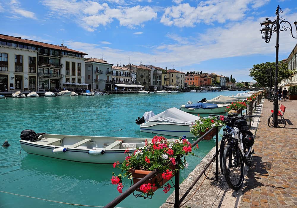 beautiful fishing boats with red flowers in front and houses at Lake Garda italy