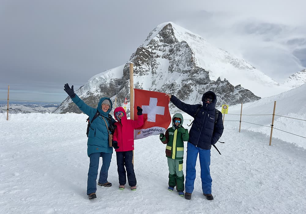 family holding Swiss flag atop Jungfraujoch